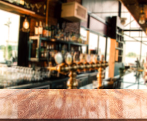 Empty wooden top table in front of abstract blurred beverage bar. Mock up for display of product