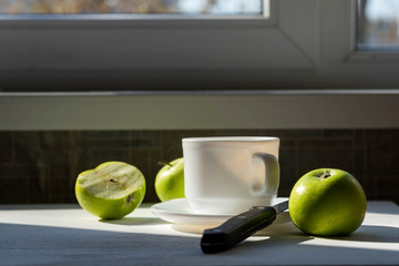 Cup of tea and green apples on a wooden table.