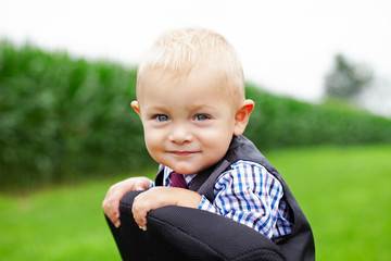 Portrait of smiling little boy sitting on office chair outdoors