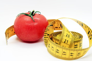a ripe tomato and a yellow measuring tape on a white background