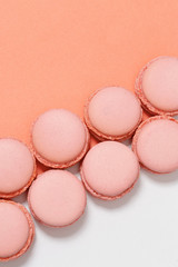 Row of macaroons on colorful background with copy space. Orange tasty round cookies. Minimal style.
