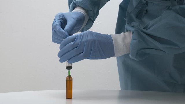 closeup on man's hands filling syringe with solution from glass vial. doctor preparing injection for patient from vaccine bottle at hospital. Medicine, healthcare, medical concept, clinic vaccination