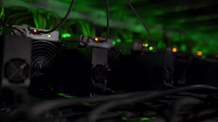 Cryptocurrency mining equipment on large farm. ASIC miners on stand racks mine bitcoin in server room. Blockchain techology application specific integrated circuit. Light effects