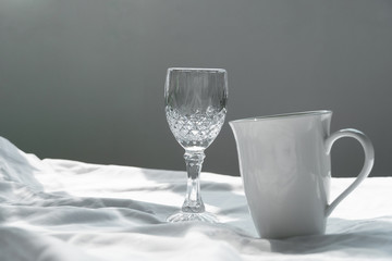 still life of white ceramic coffee cup and wine glass on fabric for food and drink background