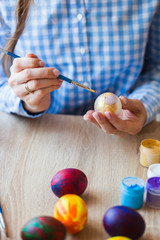 Holidays, handmade and creation concept - Girl draws on Easter egg, close-up.
