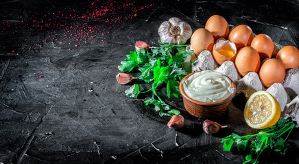 Mayonnaise with eggs, parsley and garlic cloves on dark background