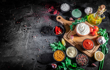 Set of sauces - ketchup, mayonnaise, mustard soy sauce, wasabi on dark background. Top view with...