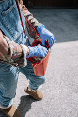 Elegant and stylish young girl with sanitary gloves searches her bag for disinfectant gel while on the street. Concept of public health and pandemic
