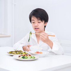 Obraz na płótnie Canvas Handsome Asian boy eating with chopsticks