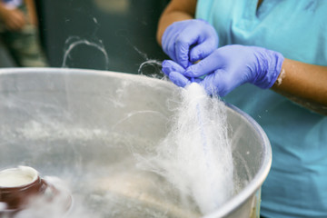 The process of preparing cotton candy in a centrifuge. Hands in rubber gloves wind sugar fibers on a stick