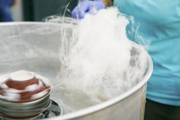 The process of preparing cotton candy in a centrifuge. Hands in rubber gloves wind sugar fibers on a stick