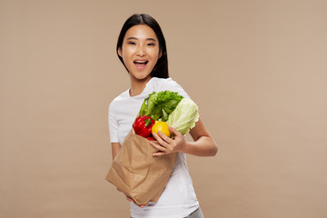 young woman holding a bag full of vegetables