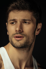 Fototapeta premium Muscle strong beautiful stripped male model with white shirt in denim gray jeans on black isolated font background