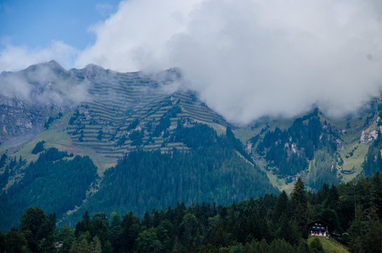Mountain landscape, snowy mountain peaks. Mountain, coniferous forests surrounded by mountains. Summer alpine village. Alps mountain range. Village in the mountains in the summer. © alexphoto1993