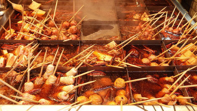 Various kinds of oden food are cooked in a spicy hot pot divided into grids with balls, tofu, seafood sticks and chili. Japanese cuisine in China.