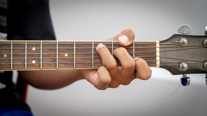 Men hands playing acoustic guitar in C chord.