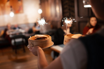 the waiter carries dishes with sparklers. life style, view from the back