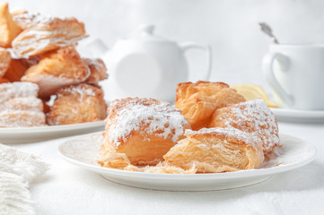 Square puff pastry cookies sprinkled with powdered sugar. Homemade. On a white plate. In the...