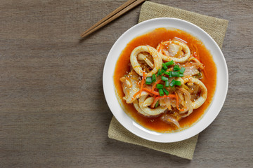 top view of stir fried squid with kimchi in a ceramic dish on wooden table. homemade style food concept.