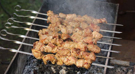 Pork shashlik kebab is fried on the grill on coals on skewers on the dacha. Background image, copy space