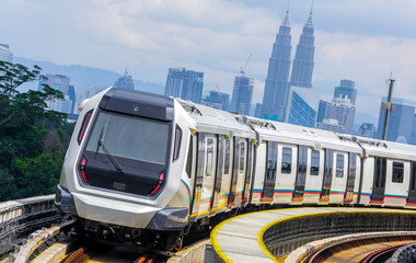 Malaysia Mass Rapid Transit (MRT) train with a background of Kuala Lumpur cityscape. People commute...