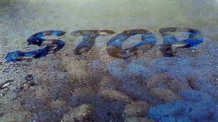 the word stop written on colored wet glass in droplets of water