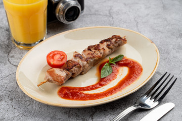 Roasted meat on a skewer with golden crust and tomato sauce, a part of kids menu of a restaurant