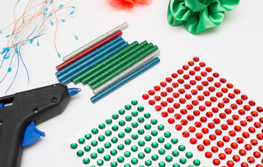 Concept of glue gun with colorful glue sticks on white background. Home hobbies crafts
