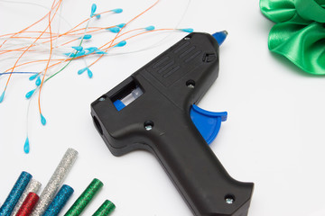 Concept of glue gun with colorful glue sticks on white background. Home hobbies crafts