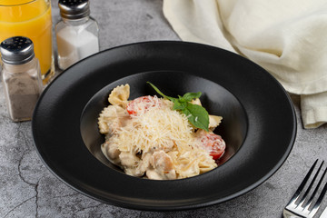 A portion of farfalle alfredo with creamy sauce and chicken breast, decorated with grated parmesan cheese