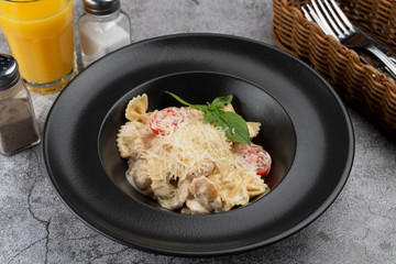 A portion of farfalle alfredo with creamy sauce and chicken breast, decorated with grated parmesan cheese