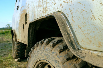 Fototapeta na wymiar dirty body gray SUV covered with dirt tires with a large tread
