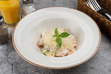 A portion of farfalle alfredo with creamy sauce and chicken breast, decorated with grated parmesan cheese