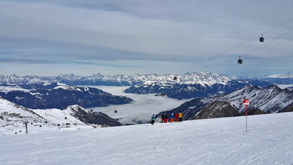 Austria sezon narciarski trasa narciarska widok z góry na dolinę pokrytą mgłą - obrazy, fototapety, plakaty