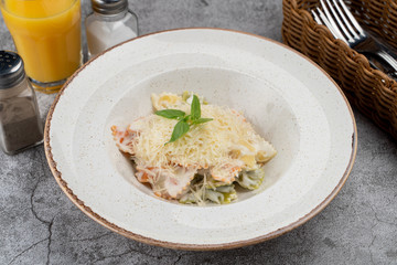 A portion of farfalle alfredo with creamy sauce and chicken breast, decorated with grated parmesan cheese