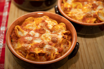 Baked pasta. Baked orecchiette with bolognese sauce (ragù alla bolognese) and mozzarella in terracotta dish. Italian cuisine. Apulian pasta.