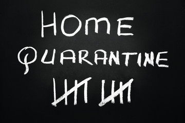 Home quarantine and strike through count days written with chalk on a blackboard