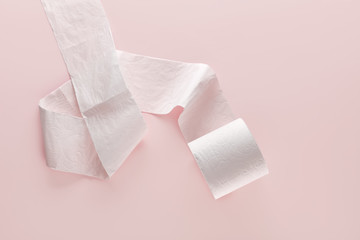 Roll of soft white toilet paper on pink background