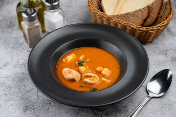 Hot and spicy tomato seafood soup with salmon, prawns and squids, close up