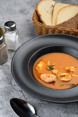Hot and spicy tomato seafood soup with salmon, prawns and squids, close up