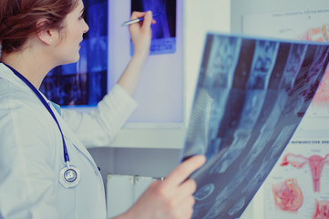 Young professional female doctor examining patient's x-ray