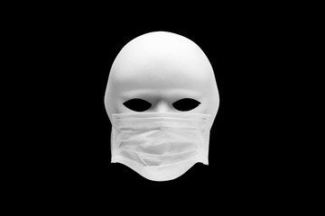 White human face mask wearing a medical mask isolated on black background