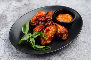 Spicy sweet and sour chicken wings with chili sauce on grey marble table