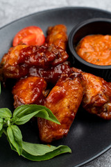 Spicy sweet and sour chicken wings with chili sauce on grey marble table