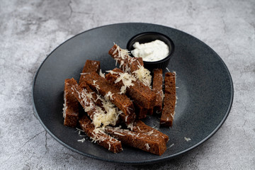Deep fried rye croutons with grated parmesan cheese and garlic sauce on grey marble background
