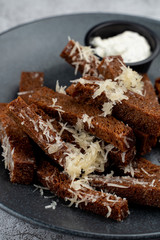 Deep fried rye croutons with grated parmesan cheese and garlic sauce on grey marble background