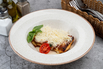 A portion of classic italian lasagna with minced meat, bechamel sauce and a lot of grated cheese on top