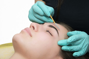 Professional beautician treatment concept. Eyelash lamination, extension performed on beautiful model. Close up portrait, young woman getting eyebrow threading, painting, macroblade shaping procedure.