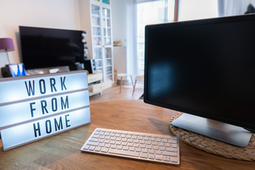 Working from home remote work inspirational social media lightbox message board next to monitor and keyboard and mouse, COVID-19 quarantine closure of all. Apartment background