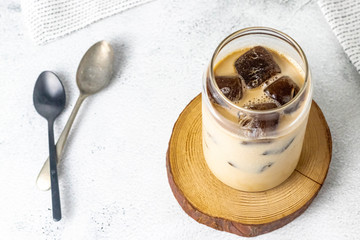 Espresso with milk and frozen coffee cubes on a white stone background